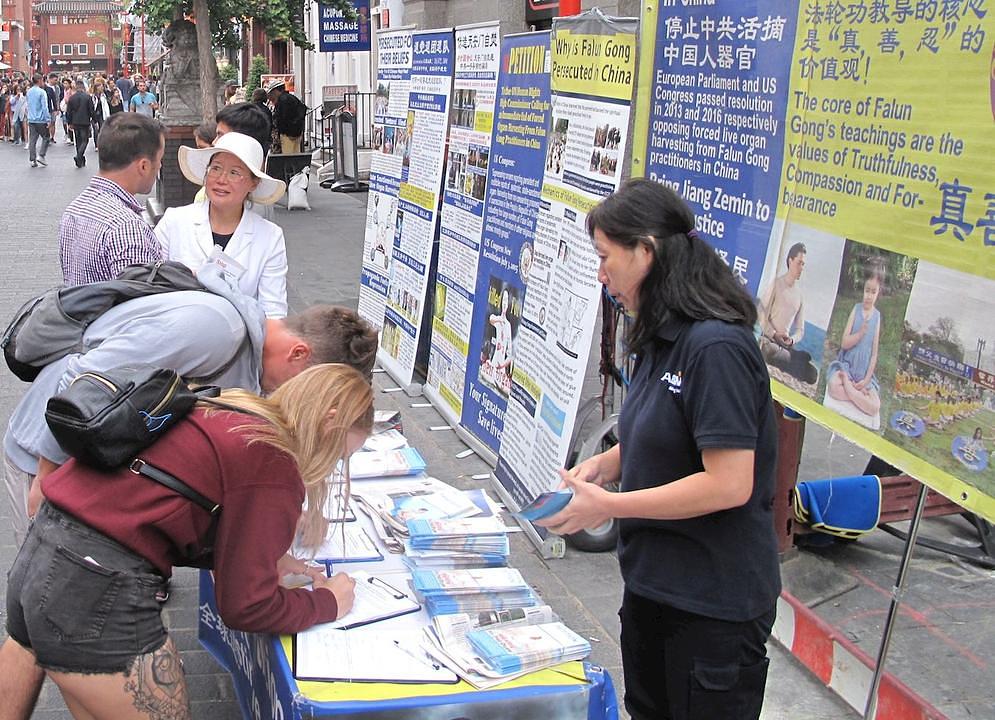 Posjetioci čitaju Falun Gong materijale i potpisuju peticiju kako bi osudili progon.