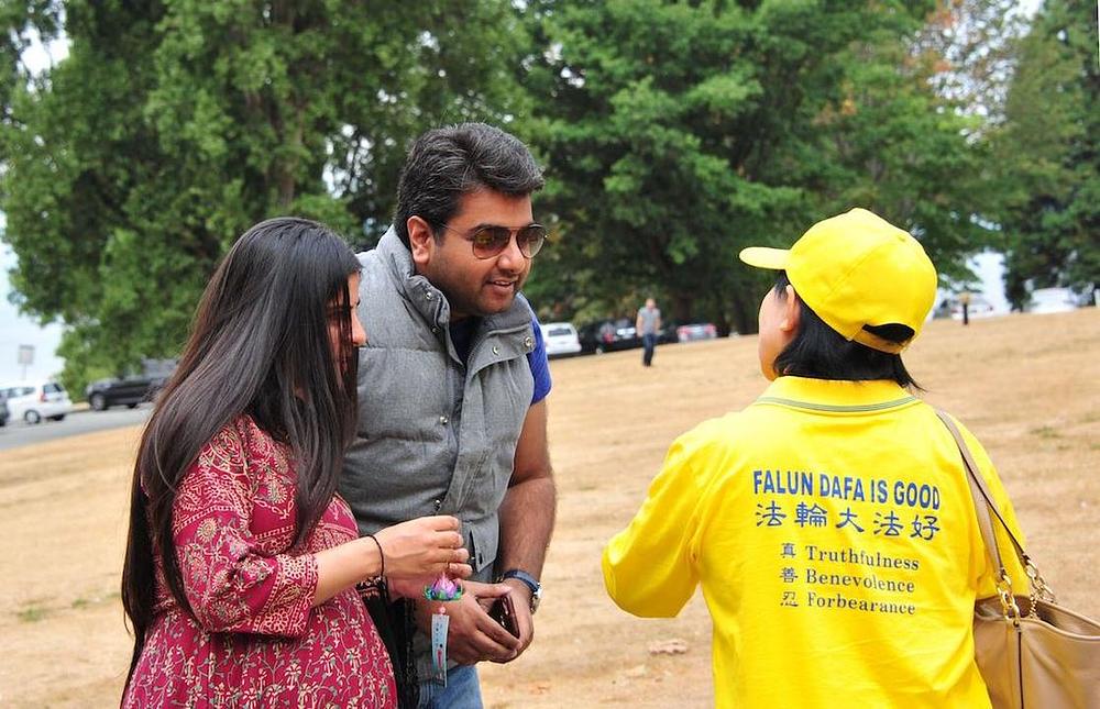 Gledaoci razgovaraju sa praktikantima i fotografišu Falun Gong grupu