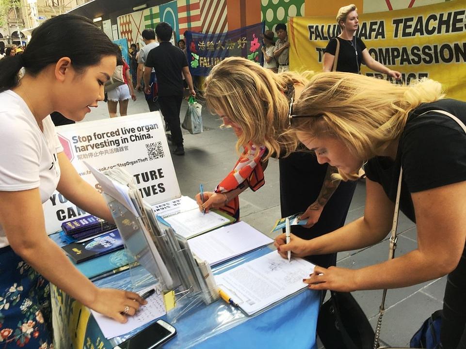  U blizini centralne željezničke stanice u Melbourneu, praktikant Falun Gonga poziva prolaznike da potpišu peticiju prije dočeka Nove godine 