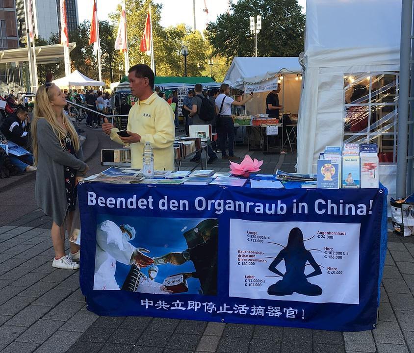 Posjetioci sajma knjige se zaustavljaju pokraj Falun Gong stola i informiraju se o praksi 