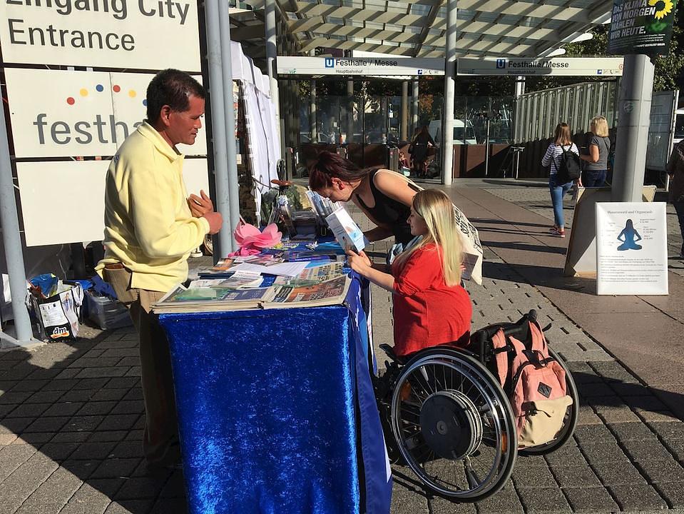 Jessica Fregin (žena u invalidskim kolicima) čita Falun Gong materijale
 