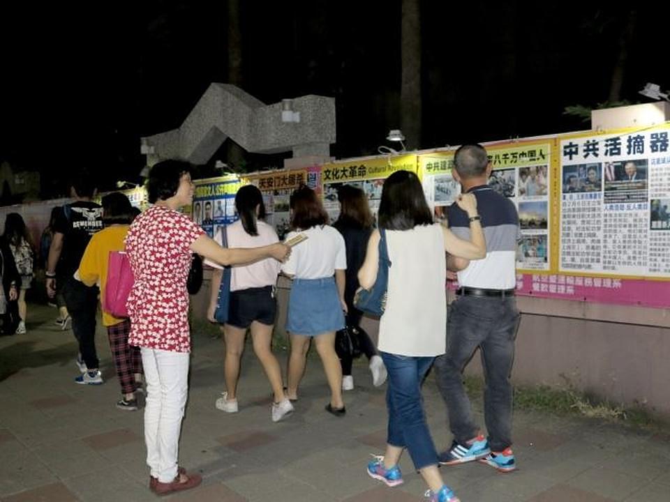 Turisti i mještani gledaju Falun Gong plakate na noćnom sajmu u Ruifengu.