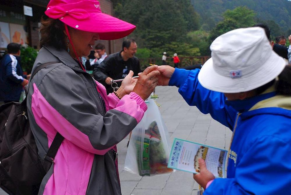 Falun Gong praktikant turistu daje informativne materijale i lotosov cvijet od papira