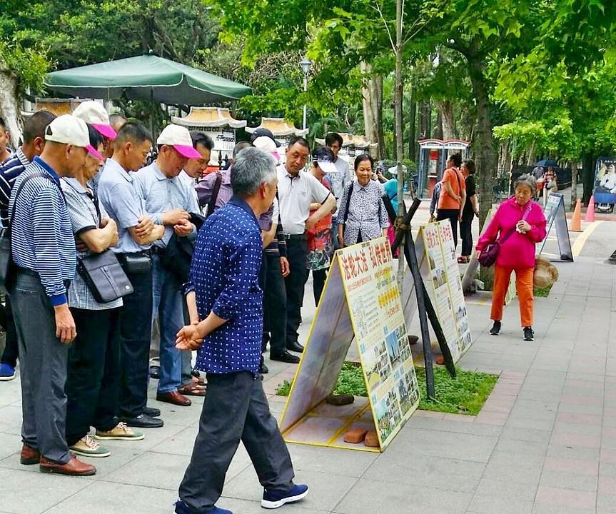 Kineski turisti zastaju pred plakatima Falun Gonga.