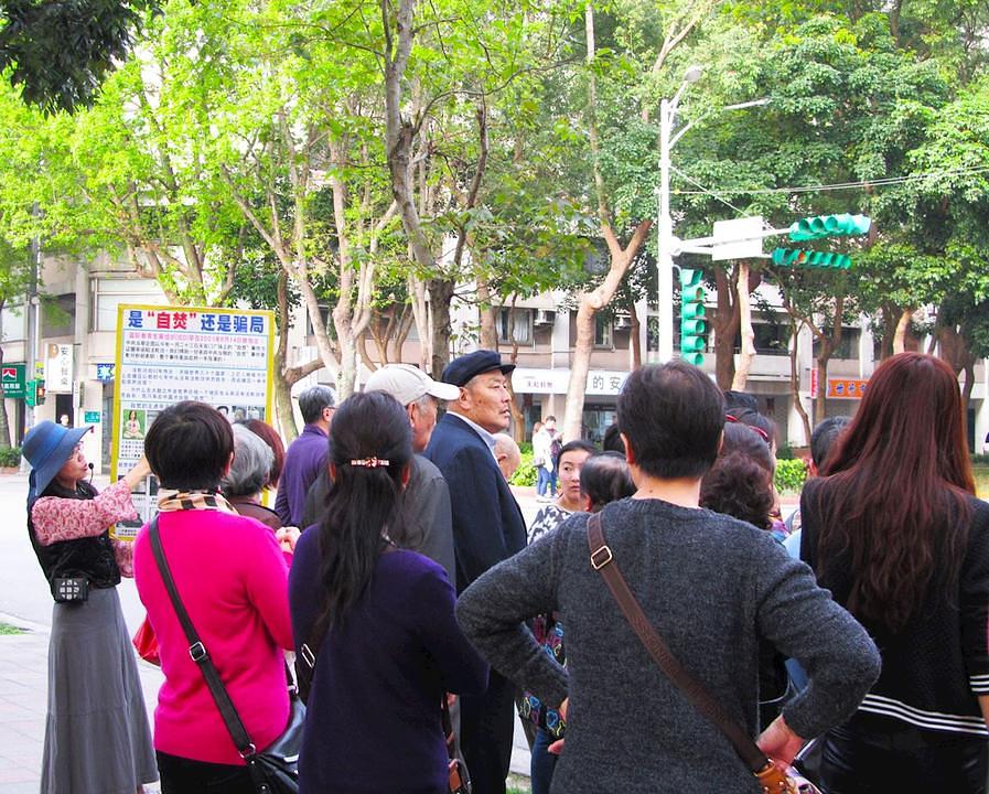 Kineski turisti slušaju praktikante kako objašnjavaju istinu o Falun Gongu.