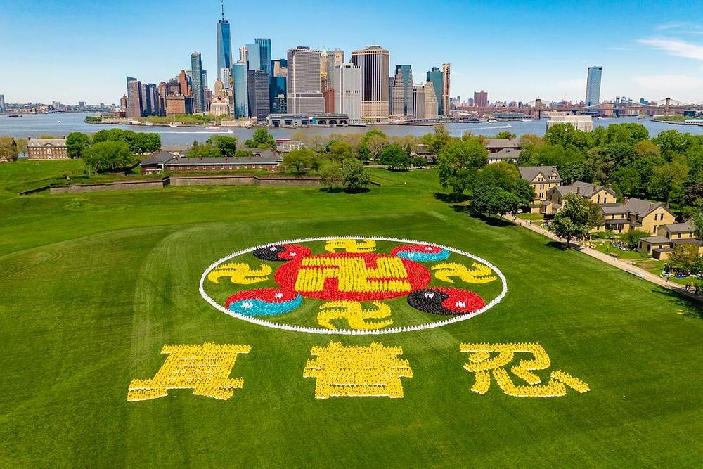 Pet hiljada Falun Dafa praktikanata se 18. maja 2019. okupilo na njujorškom Guvernerovom ostrvu da bi svojim tijelima formirali veliki simbol Faluna i kineske znakove sa značenjem Istinitost, Dobrodušnost i Tolerancija. 