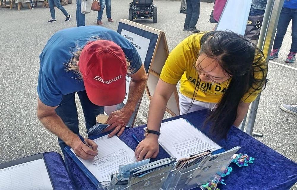 Prolaznik potpisuje peticiju kojom protestuje protiv progona Falun Gonga u Kini.