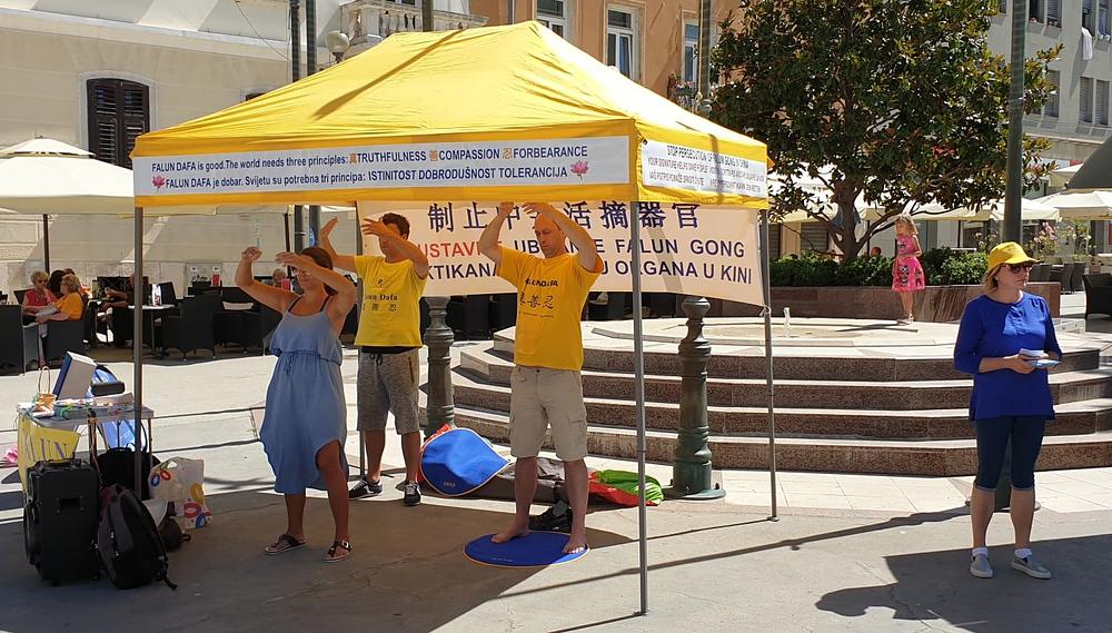 Praktikanti izvode Falun Dafa vježbe u centru Pule, pored gradske tržnice