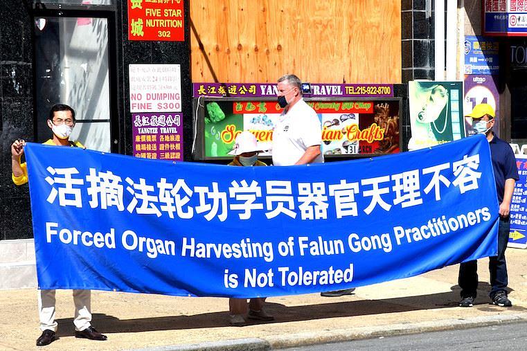 Falun Gong praktikanti u kineskoj četvrti u Filadelfiji drže istaknute transparente u avgustu mjesecu 2020. godine.