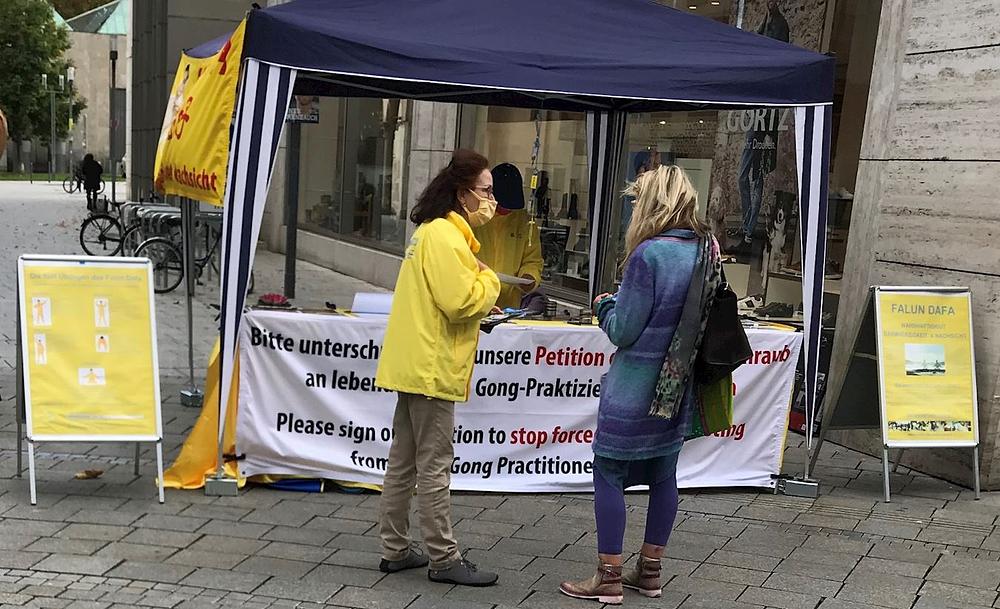 Prolaznici se zaustavljaju kako bi saznali više o Falun Dafa.