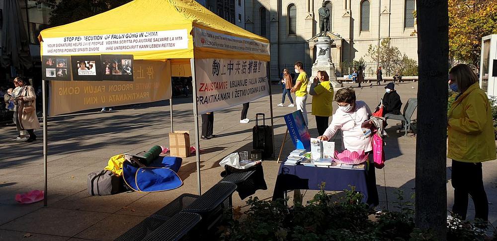  Skupina praktikanata pokazuju vježbe, dok preostali praktikanti razgovaraju s prolaznicima te ih informiraju o Falun Dafa, progonu i žetvi organa u Kini