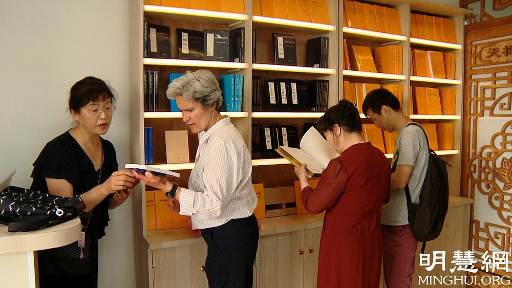 Beatrice (druga s lijeve strane) razgovara sa zaposlenicom u trgovini kako odabrati knjige koje su joj potrebne.