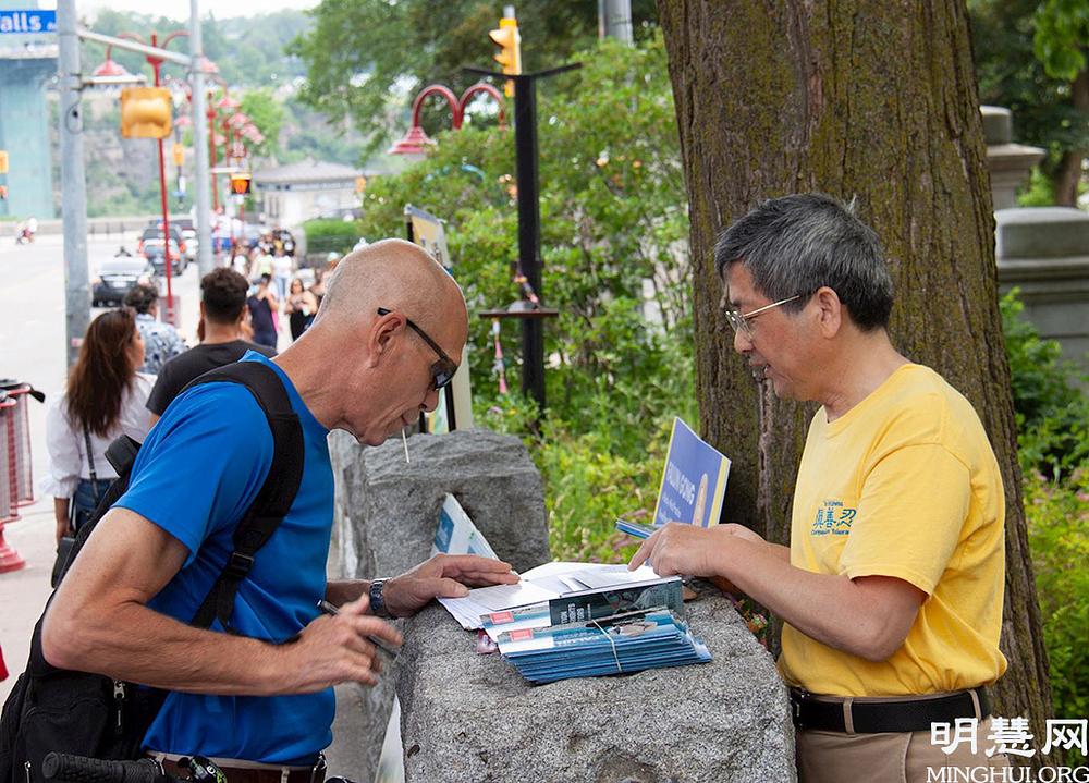 Turistu se na trenutak zaustavljaju da bi učili o Falun Dafa.