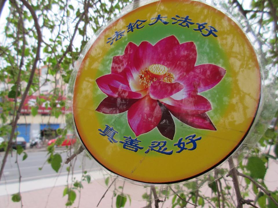 Iznad lotusa stoji "Falun Dafa je dobar", a ispod "Istinitost, Dobrodušnost i Tolerancija su dobri"