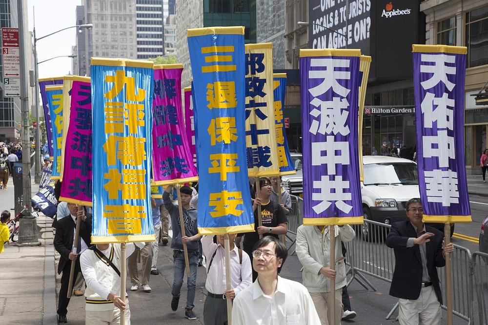 Transparent na čelu povorke sa natpisom (sa lijeva na desno): Devet Komentara šire Dobru sreću; Napustite KKP za spas budućnosti; Nebesa će uništiti KKP; Nebesa štite Kinu.