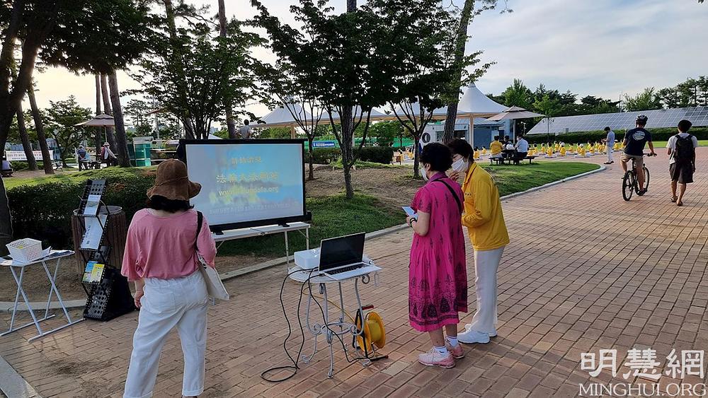 Pješaci gledaju video zapise o Falun Gongu i progonu u Kini