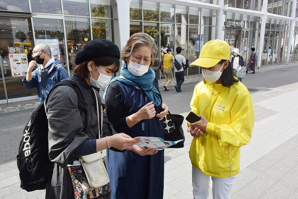 Gospođa Yamashita (u sredini) i njena unuka (lijevo) čitaju informacije o Falun Dafa.