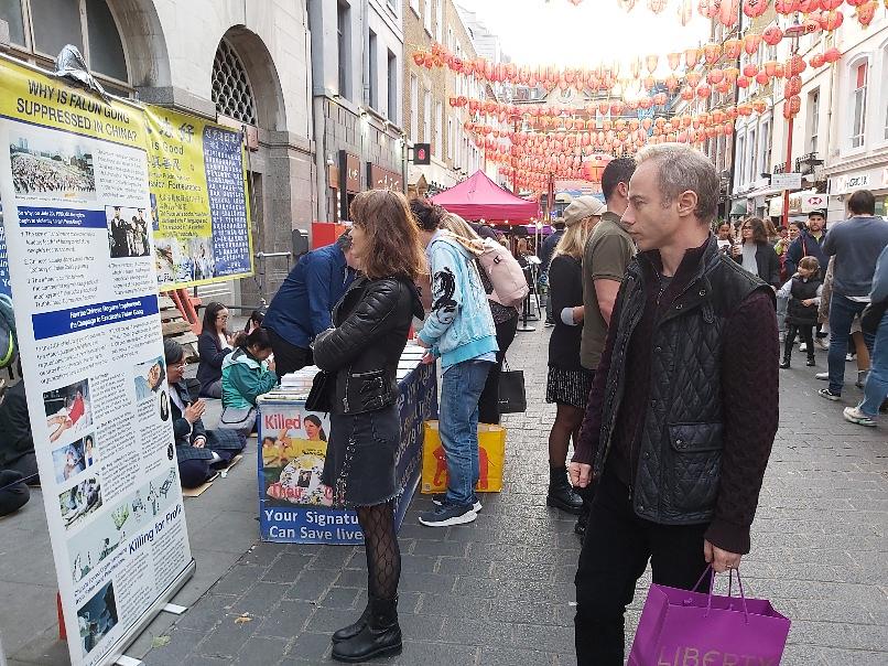 Ljudi čitaju plakate o Falun Dafa u kineskoj četvrti u Londonu. 