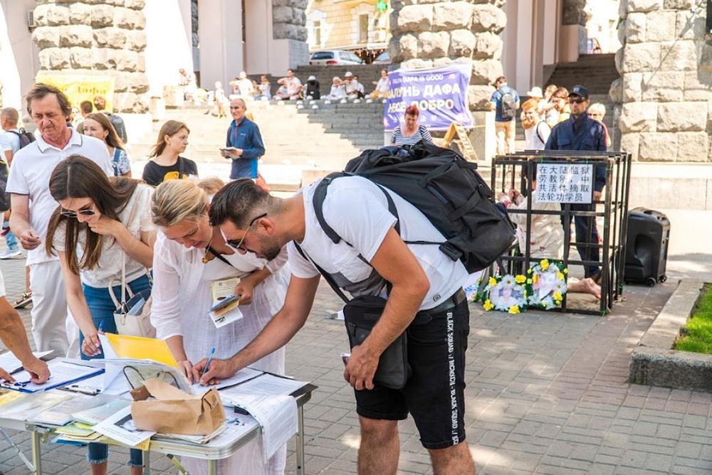Prolaznici potpisuju peticiju kojom se poziva na prekid progona Falun Dafa od strane KPK na informativnom Dafa štandu u centru Kijeva.