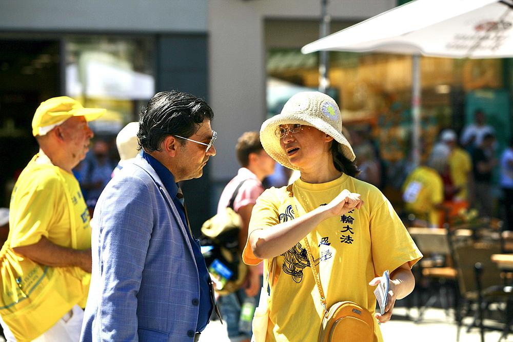  Ljudi razgovaraju sa praktikantima o Falun Gongu.