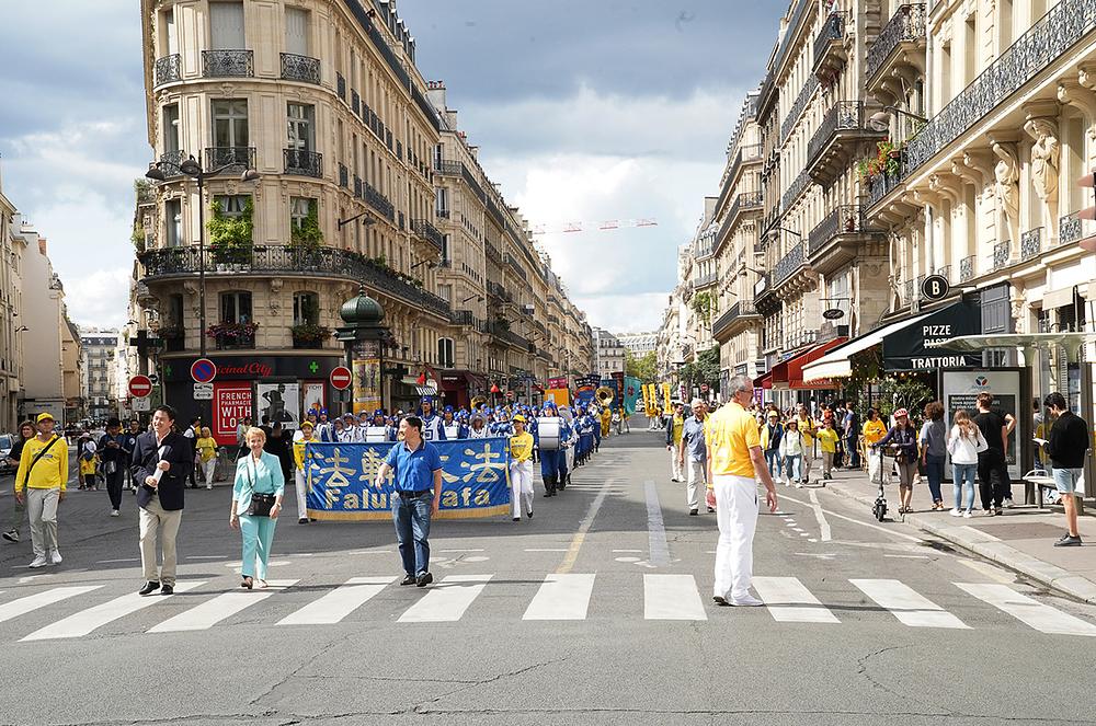 Parada Falun Dafa praktikanata u središtu Pariza 26. kolovoza. Françoise Hostalier, bivša francuska ministrica obrazovanja i zamjenica voditelja francuske delegacije pri Europskoj komisiji (žena u svijetloplavom odijelu u prvom redu) sudjelovala je u paradi.