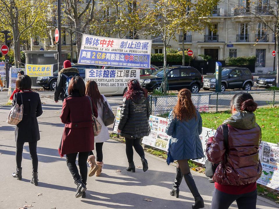 Kineski turisti prolaze pored Falun Gong info štanda kraj Ajfelovog tornja u Parizu.