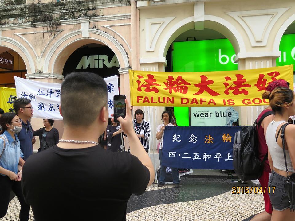 Kineski turisti slikaju Falun Gong manifestaciju.