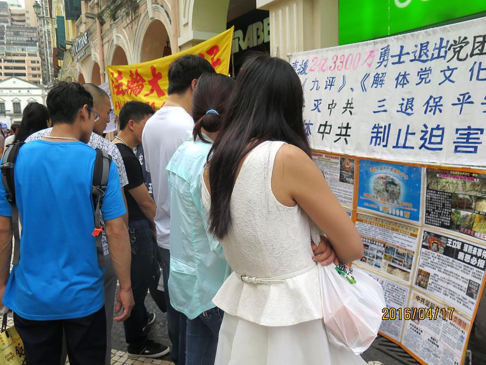 Kineski turisti čitaju o Falun Gongu.