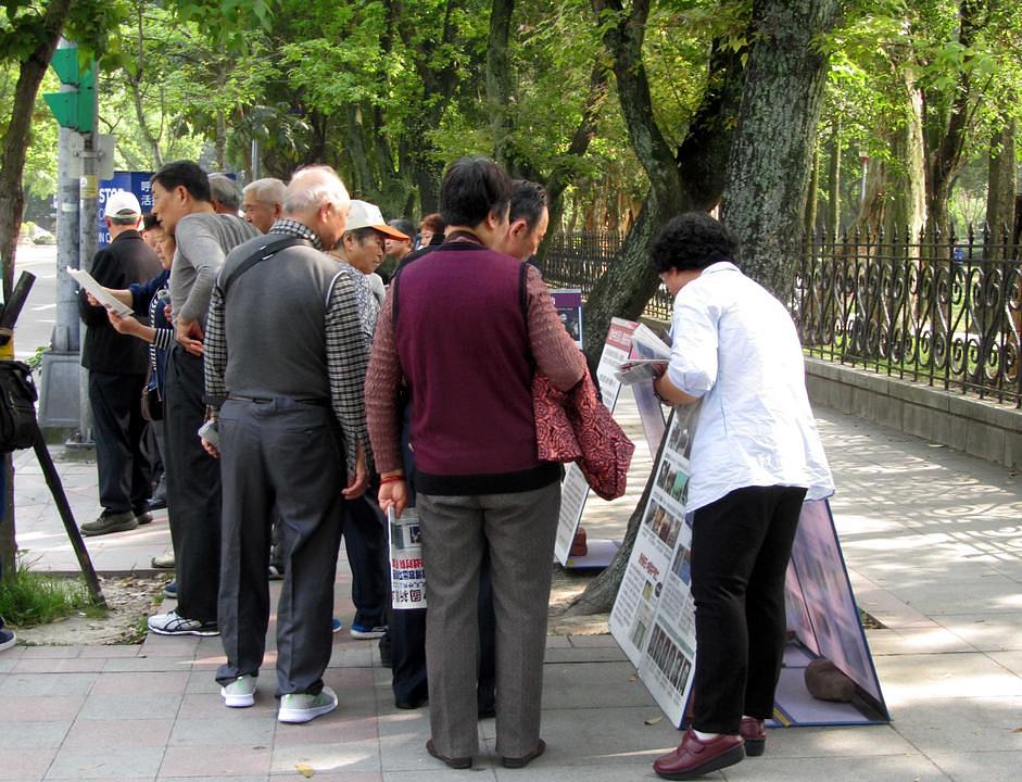 Kineski turisti proučavaju Falun Gong materijale.