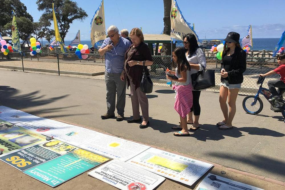 Prolaznici se zaustavljaju kako bi pročitali Falun Dafa plakate