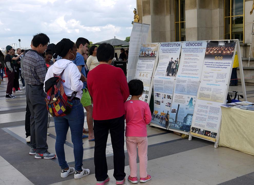 Posjetioci čitaju plakate i informišu se o brutalnom progonu Falun Gonga u Kini 
