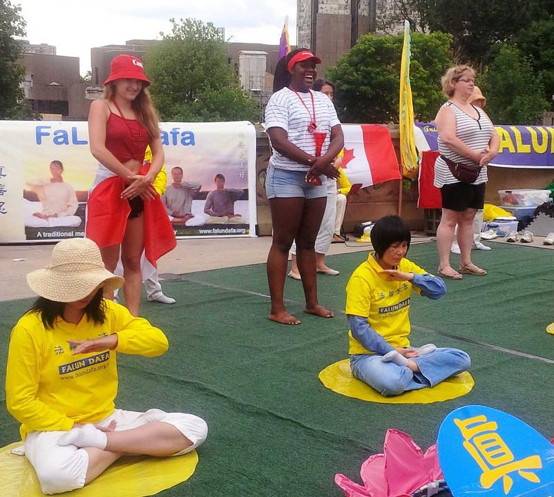 Turisti (u drugom redu) uče Falun Gong vježbe 