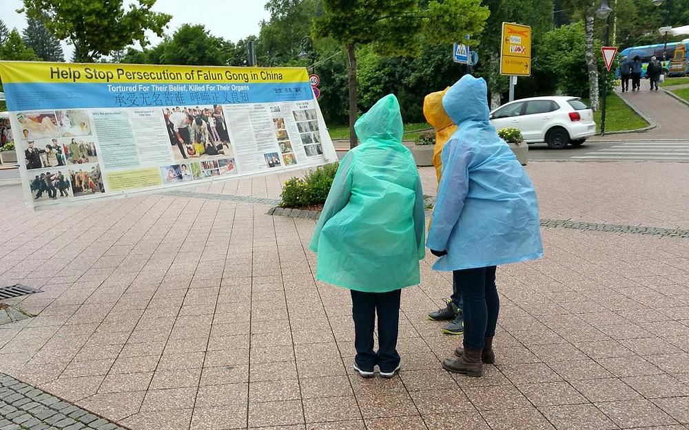 Turisti čitaju plakate o Falun Gongu i njegovom progonu u Kini.