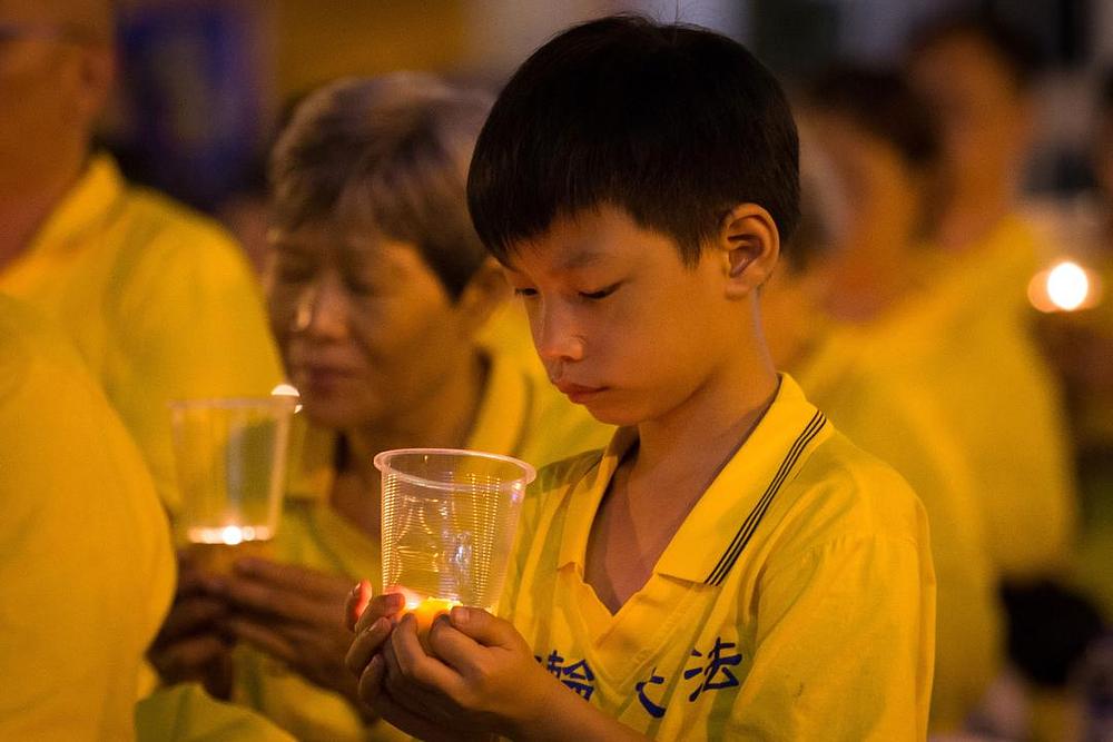 Dječak drži u ruci svjeću u znak sjećanja na praktikante Falun Gonga mučene do smrti u kopnenoj Kini, zato što su se odbili odreći svoje vjere.