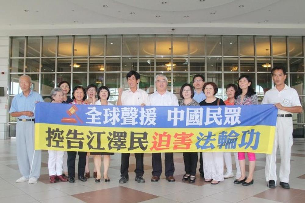 Li Wenzheng (u sredini), član gradskog vijeća grada Tainana sa praktikantima Falun Gonga.
Na transparentu stoji: „Globalna podrška sudskim tužbama protiv Jiang Zemina zbog progona Falun Gonga“.
