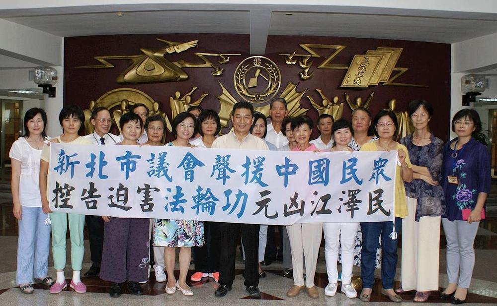 Zajednička fotografija gradskog vijeća Novog Taipeija. Na transparentu piše: „Gradsko vijeće Novog Taipeija podržava tužbe kineskih građana protiv Jiang Zemina, pokretača progona Falun Gonga.“ 