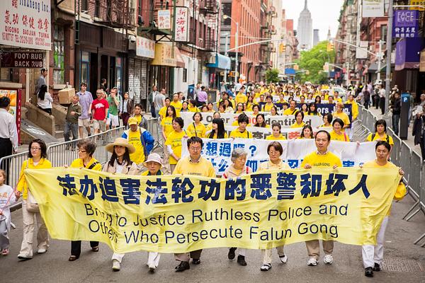 Praktikanti drže transparent sa natpisom: „Dovedite pred lice pravde okrutnu policiju i druge koji progone Falun Gong.“