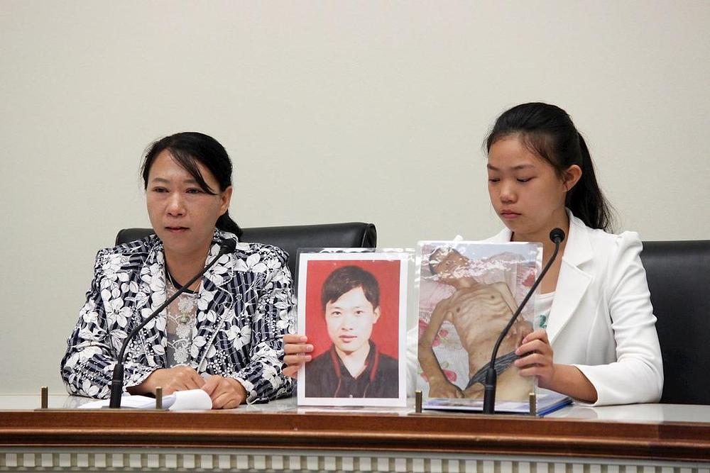 Chi Lihua (lijevo) i njena kćerka Xu Xinyang (desno) na forumu. Xu drži dvije slike njenoga oca Xu Daweija. Fotografija lijevo je napravljena prije nego je Xu Dawei bio uhapšen, a slika desno je napravljena nakon njegovog puštanja na slobodu.