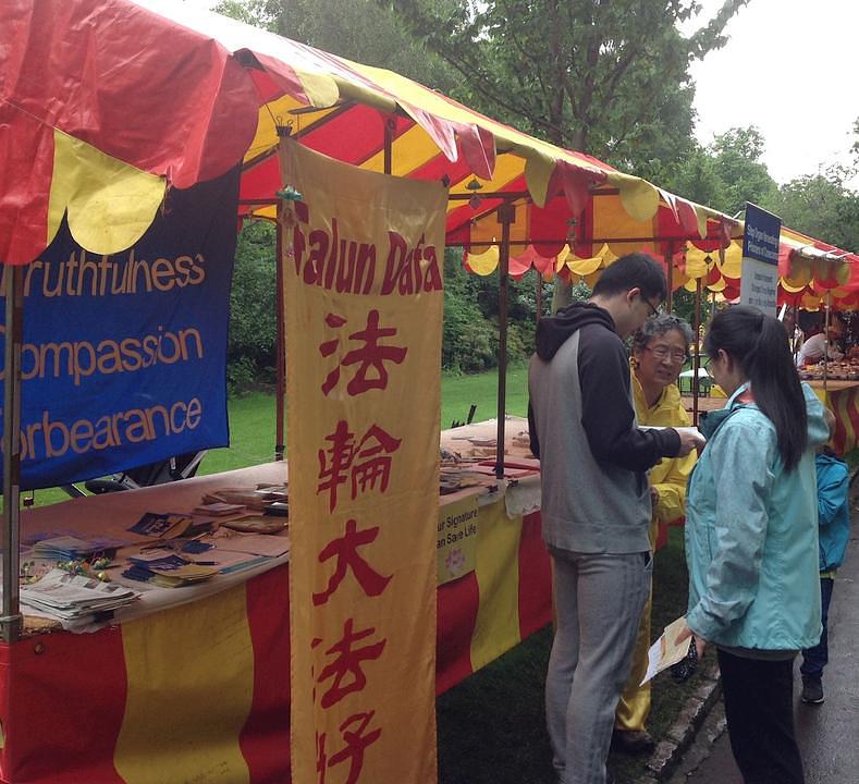 Praktikanti Falun Gonga predstavljaju Falun Gong posjetiocima. Mnogi su se ljudi zaustavili kako bi saznali više o Falun Gongu.