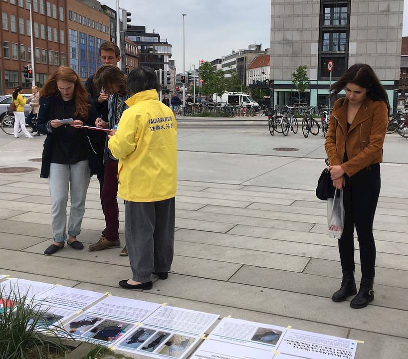 Prolaznici čitaju informacije o Falun Gongu i potpisuju peticiju protiv KKP.