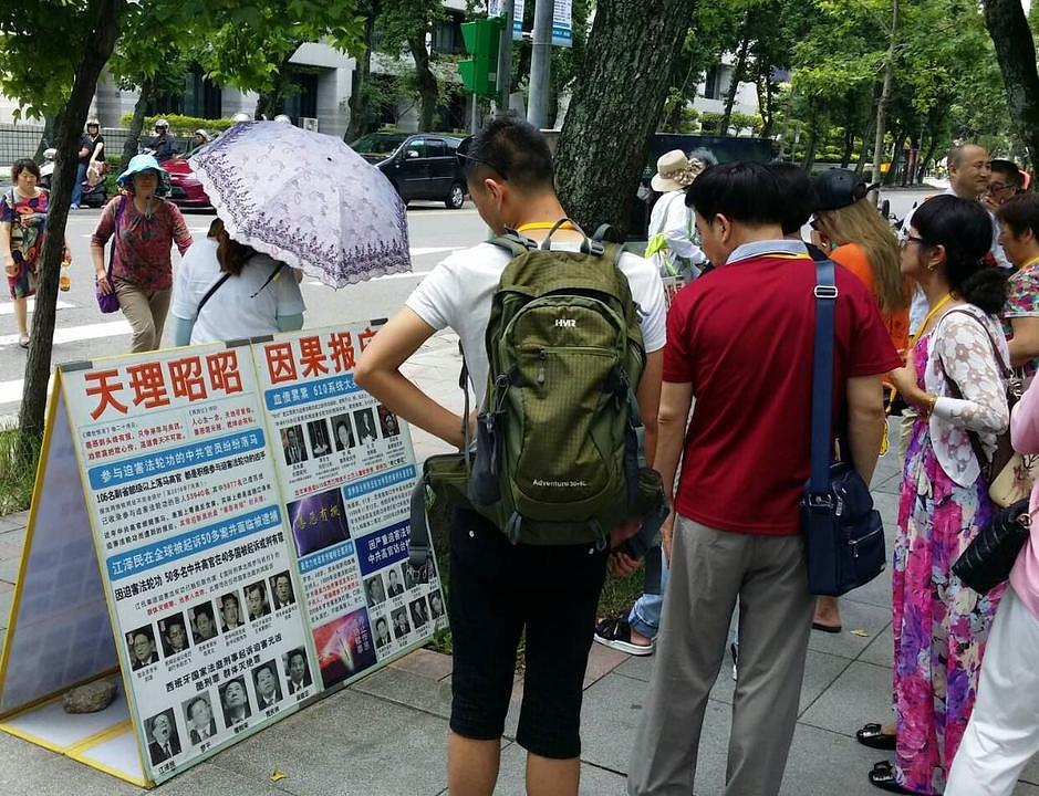 Kineski turisti gledaju izložene Falun Gong plakate.