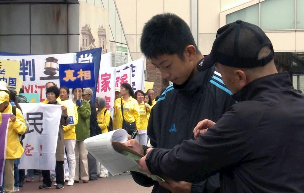 Ljudi duž puta kojim se kretala parada potpisuju peticiju podrške naporima Falun Dafa praktikanata za privođenja bivšeg lidera KPK pred lice pravde 