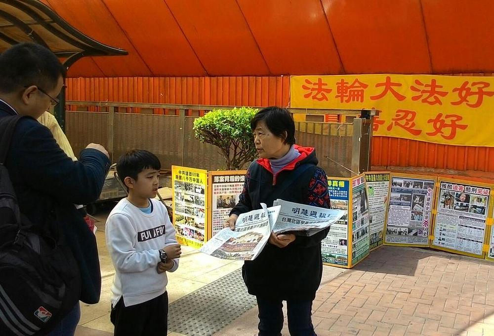 Gđa Zheng distribuira novine na Falun Gong štandu 