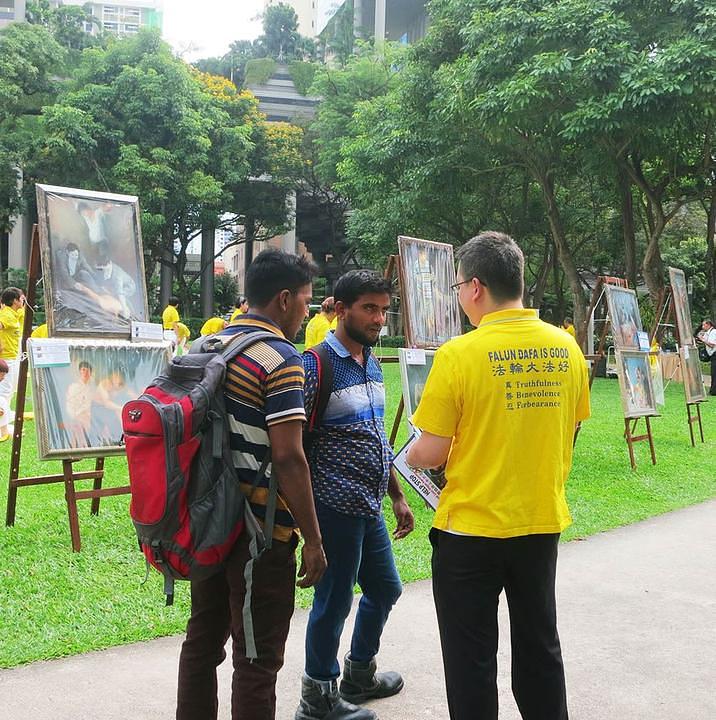 Prolaznici se zaustavljaju kako bi više saznali o Falun Gongu. 