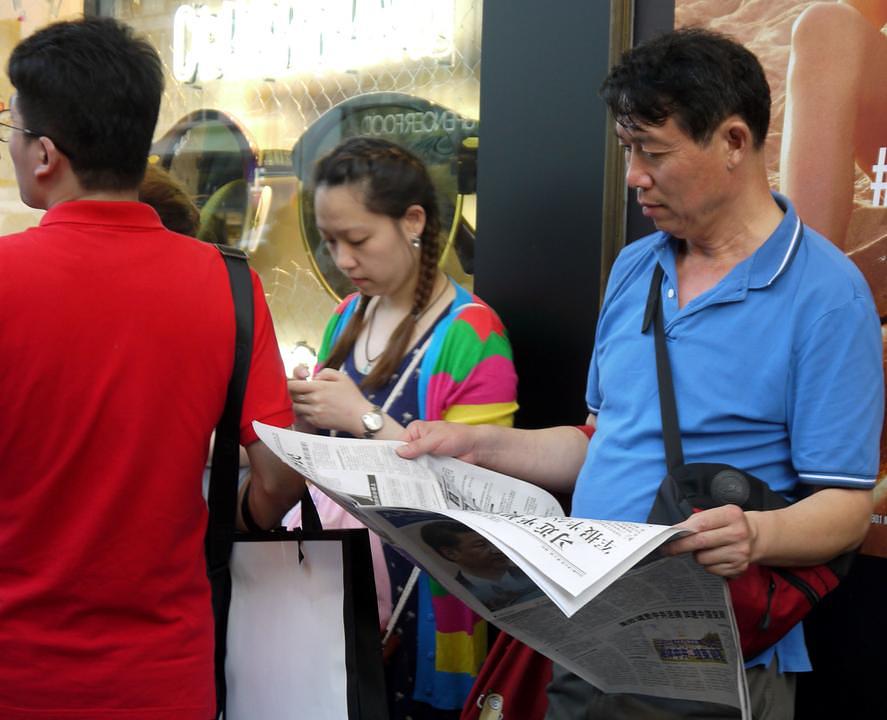 Kineski turisti ispred galerije Lafajet čitaju o Falun Gongu.