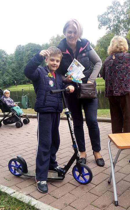 Mladi dječak drži u ruci papirni lotosov cvijet koji su napravili praktikanti, a njegova majka drži u ruci Falun Gong prospekte. 