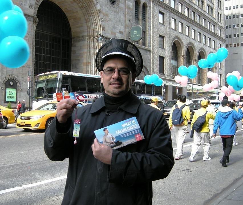 Rey, rukovodilac sigurnosti u velikom hotelu, drži u rukama Falun Gong letak i ručno izrađen lotosov cvijet.