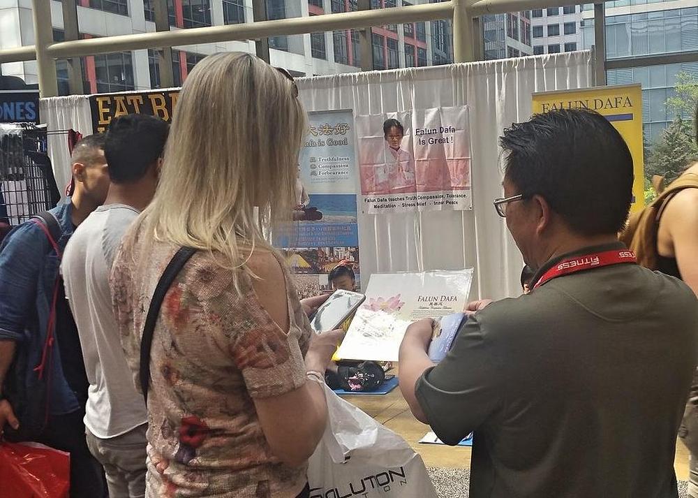 Posjetioci zastaju kraj Falun Gong štanda kako bi saznali više o Falun Gongu.