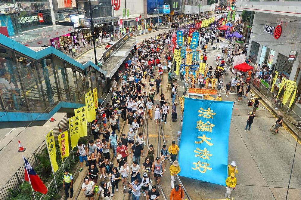 Praktikanti Falun Gonga na paradi (desna strana slike sa transparentima u plavoj i žutoj boji). Na velikom transparentu piše: "Falun Dafa je dobar." 