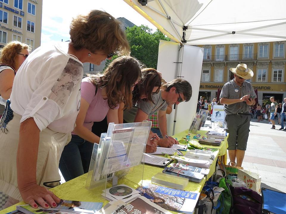 Ljudi potpisuju peticiju da bi protestvovali protiv progona Falun Gonga u Kini.